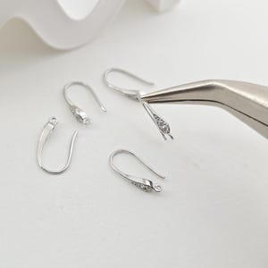 May include: Four silver earring hooks with clear crystal accents. The hooks are designed to be used for jewelry making.