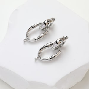 May include: A pair of silver-toned metal earring findings with a unique oval link design. The links are connected with a smaller oval ring.