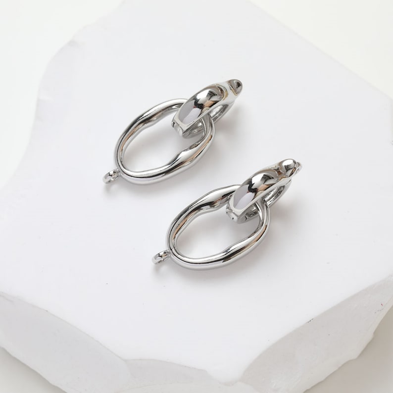 May include: A pair of silver-toned metal earring findings with a unique oval link design. The links are connected with a smaller oval ring.