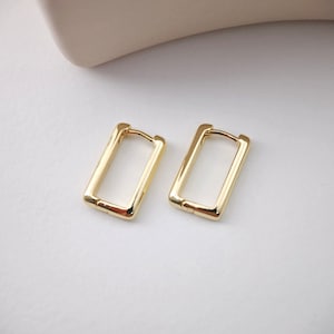 May include: A pair of gold-toned rectangular hoop earrings. The earrings are simple and minimalist in design.