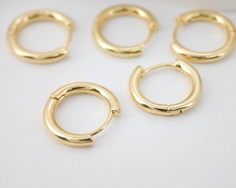 Op de afbeelding: Vier gouden creolen in verschillende maten. De oorbellen zijn simpel en elegant, met een gladde, gepolijste afwerking.