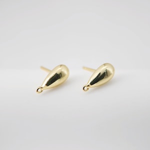 May include: A pair of gold teardrop-shaped earring findings. The findings have a small loop at the bottom and a post at the top.