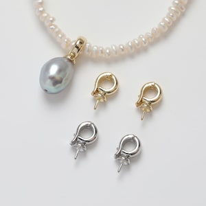 Puede incluir: Un collar de perlas con un colgante de perla gris y cuatro cierres de oro y plata. Los cierres están diseñados para sujetar una perla u otra gema.