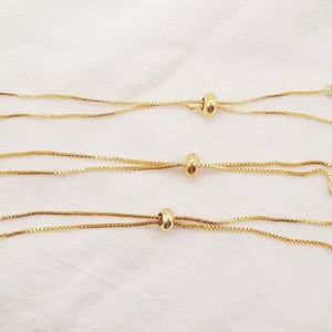 May include: Three gold chain bracelets with adjustable sliding beads and crystal accents. Each bracelet has a different style of crystal accent.