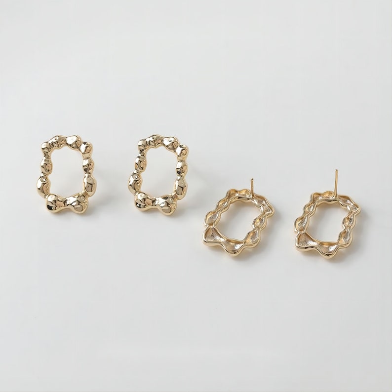 May include: A pair of gold-toned earrings with a unique, textured, irregular oval shape. The earrings are shown on a white background.
