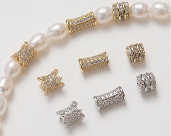 May include: A set of gold and silver tone jewelry connectors with clear cubic zirconia stones. The connectors are in the shape of a cylinder and a star.