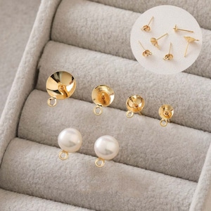 May include: Gold earring findings in a variety of styles, including round, teardrop, and post-style. The findings are displayed in a velvet-lined jewellery box.