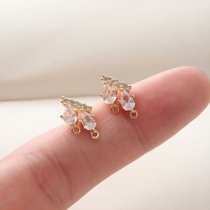 May include: A pair of gold-tone earring charms with clear teardrop-shaped crystals and smaller round crystals.