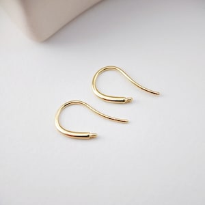 Peut inclure: Une paire de crochets d'oreille dorés. Les crochets sont en métal et ont une finition lisse et polie.