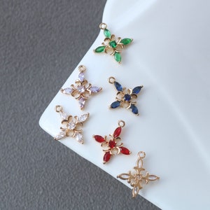 Puede incluir: Seis abalorios de metal dorado en forma de estrella de cuatro puntas con un centro de cristal. Los abalorios están decorados con cristales de diferentes colores: verde, blanco, azul, rojo y transparente.