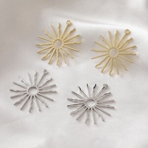 May include: Four metal sunburst charms, two gold and two silver, with a hole at the top for attaching to jewelry or other crafts.