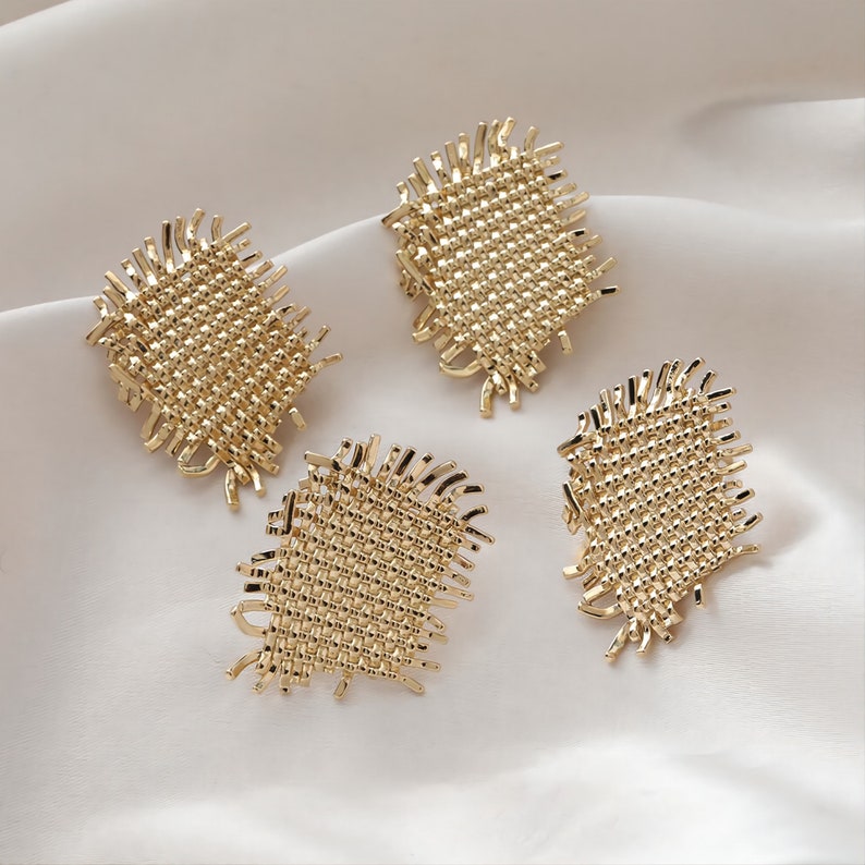 May include: Four gold-toned woven square earrings with a frayed edge.