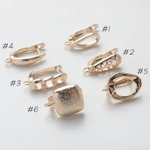 Könnte beinhalten: Eine Sammlung von sechs goldfarbenen Ohrring-Anhängern, jeweils mit einem einzigartigen Design. Zu den Stilen gehören eine Tropfenform, ein filigranes Design, eine Kette, ein Quadrat und ein Oval. Die Anhänger werden auf einer weißen Oberfläche präsentiert.