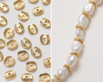 May include: A collection of gold-toned metal beads and a strand of white pearl beads. The metal beads are round and have a raised design. The pearl beads are irregular in shape.