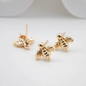 May include: A pair of gold bee stud earrings. The earrings are small and delicate, with a detailed bee design.