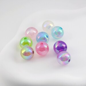 May include: Assortment of iridescent round beads in various pastel colors, including pink, purple, green, and blue. The beads have a smooth, glossy finish and are perfect for crafting.