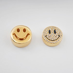 May include: Two gold-tone smiley face charms. One charm has a simple outline, while the other is encrusted with clear rhinestones.