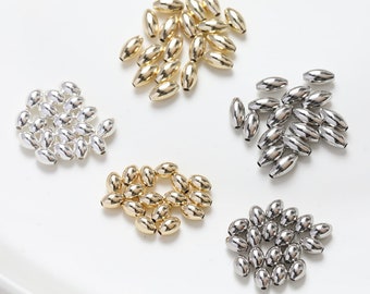 May include: Assortment of oval-shaped metal beads in gold, silver, and nickel finishes. The beads are arranged in four groups on a white surface.