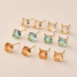 May include: A set of 10 gold-tone earring studs with square-shaped clear, blue, and orange gemstones.