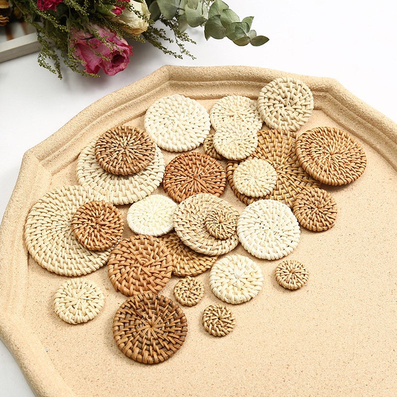 May include: A selection of woven rattan coasters in varying sizes and shades of beige and brown. The coasters are displayed on a light beige tray, highlighting their natural textures and circular designs. Perfect for home decor.