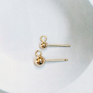 May include: Two gold-toned earring posts with a small ball at the end of each post. The posts are designed to be used with a variety of earring charms.