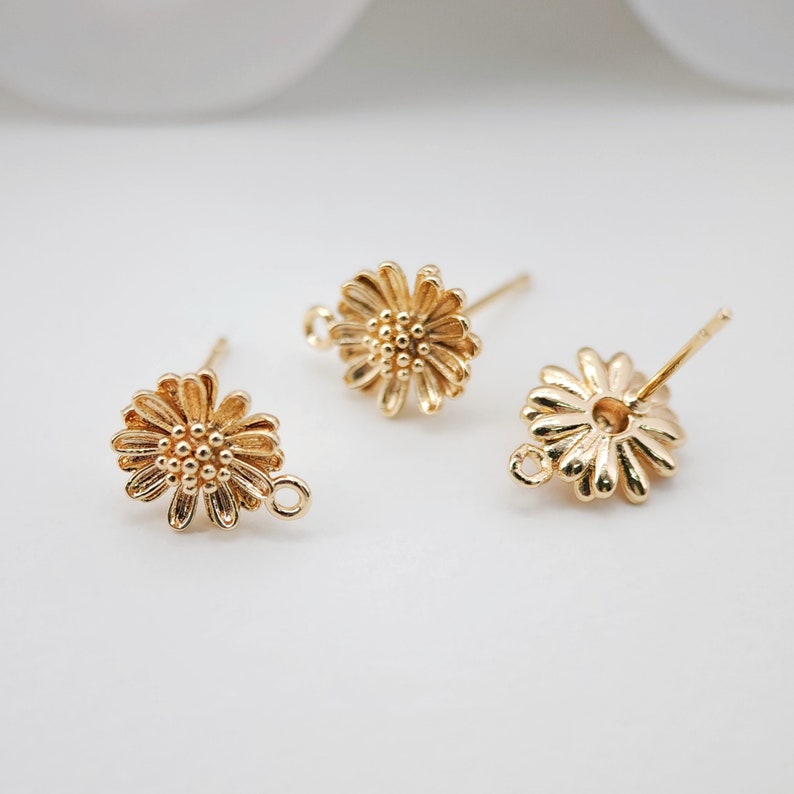 May include: Three gold-toned flower-shaped earring findings with a loop on one side and a post on the other.