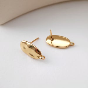 May include: Two gold-toned oval earring blanks with a post and a loop on the side.