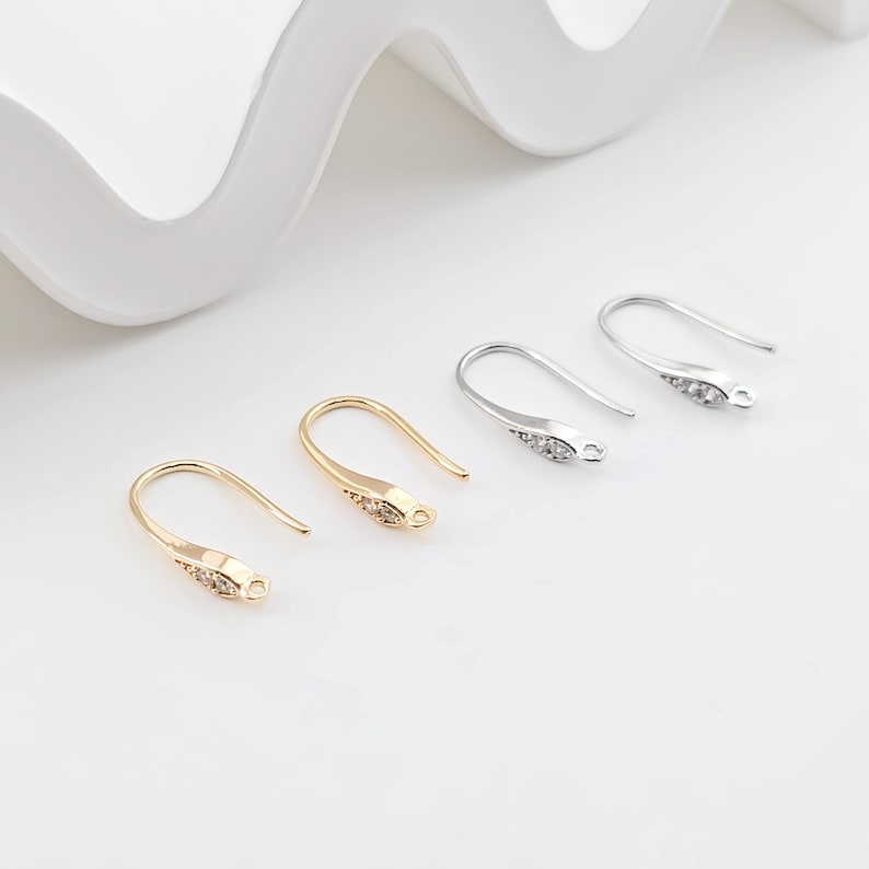 May include: Four earring hooks with a clear crystal design. Two hooks are gold and two are silver.