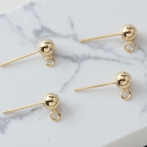 Può includere: Quattro perni per orecchini dorati con una piccola sfera nella parte superiore e un anello nella parte inferiore.
