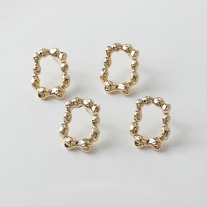 May include: Three gold-toned earrings with a textured, irregular oval shape. Each earring has a small, round hole at the top for attaching to a post.