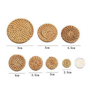 May include: A set of woven rattan coasters in various sizes, ranging from 2.5 cm to 6 cm in diameter. The natural brown coasters are displayed on a white surface, highlighting their circular design and texture.