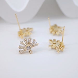 May include: Gold tone earring findings with a fan-shaped design featuring clear cubic zirconia stones. The findings have a loop at the top for attaching a dangle charm.