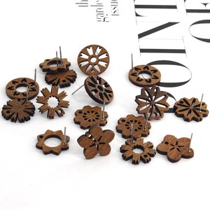 Könnte beinhalten: Eine Sammlung von 12 Holzohrringen mit filigranen Laser-Schnitten. Die Ohrringe sind braun und zeigen verschiedene florale und geometrische Muster.