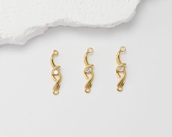 May include: Three gold-coloured jewellery connectors with a curved design. Each connector features a small, clear gemstone and a loop at each end for attachment. The connectors are displayed on a white surface.