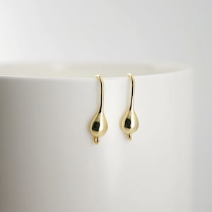 May include: A pair of gold-toned teardrop-shaped earring hooks. The hooks are made of metal and have a smooth, polished finish.