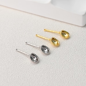 Könnte beinhalten: Vier kleine Löffel, zwei silberne und zwei goldene, sind diagonal auf einer weißen Oberfläche angeordnet. Die Löffel haben einen strukturierten Griff und eine kleine, abgerundete Schale. Die Löffel sind wahrscheinlich für dekorative Zwecke oder zur Schmuckherstellung.