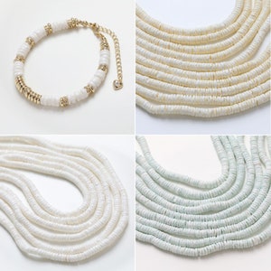 May include: Four necklaces made of white and light green shell beads. The necklaces are layered and arranged in a square format. The top left necklace is a single strand with gold accents. The top right necklace is a multi-strand necklace. The bottom left necklace is a multi-strand necklace. The bottom right necklace is a multi-strand necklace.