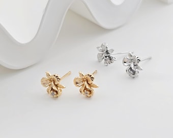 May include: A pair of gold and silver flower stud earrings with a small clear stone in the center of each flower.