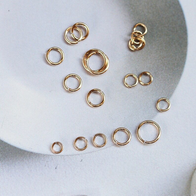 May include: A collection of gold jump rings of various sizes, perfect for jewelry making.