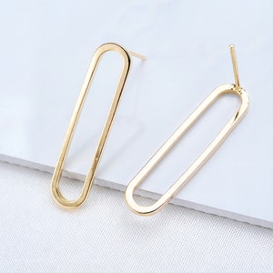 May include: A pair of gold oval-shaped earrings with a simple design. The earrings are made of metal and have a post back.