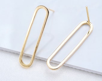 Puede incluir: Un par de pendientes ovalados de oro con un diseño sencillo. Los pendientes están hechos de metal y tienen un cierre de poste.