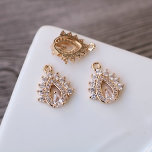 Puede incluir: Tres colgantes de gota de agua de tono dorado con detalles de cristal transparente. Los colgantes tienen un bucle en la parte superior para sujetarlos a joyas.