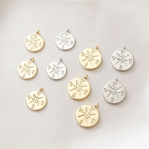 Peut inclure: Neuf breloques de compas en or et en argent avec un motif d'étoile. Les breloques sont de tailles différentes et ont une boucle en haut pour être attachées à un collier ou un bracelet.
