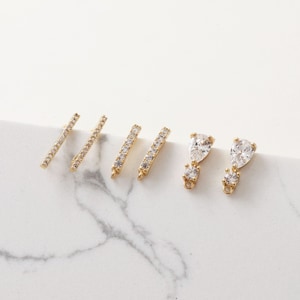 May include: Four pairs of gold-tone earring findings with clear cubic zirconia stones. Two pairs feature a straight bar design and two pairs feature a teardrop design.