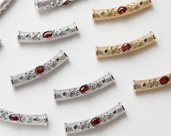 May include: Assortment of silver and gold tone metal bead spacers with red and green gemstones. Each spacer features an ornate design.