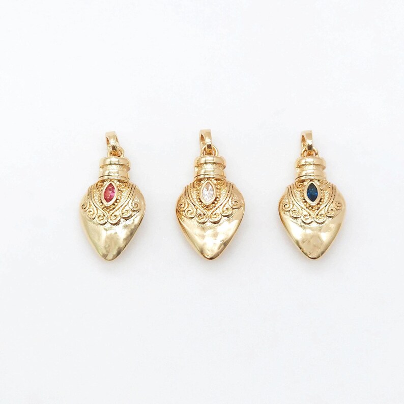 May include: Three gold heart-shaped pendants with ornate designs. Each pendant features a different colored gemstone: red, white, and blue.