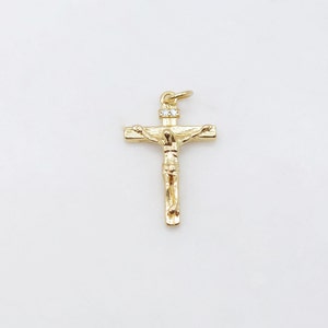 May include: A gold-toned crucifix pendant with a small clear rhinestone at the top.