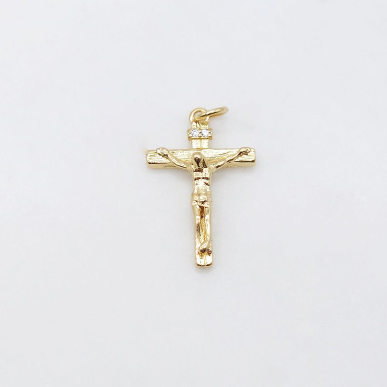 May include: A gold-toned crucifix pendant with a small clear rhinestone at the top.