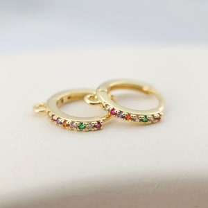 May include: A pair of gold hoop earrings with a colourful rainbow of small gemstones set into the band.