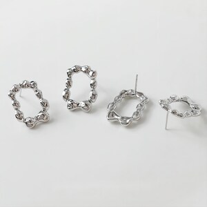 May include: Three silver earrings with a unique, organic, and textured oval shape. The earrings are designed with a post back.